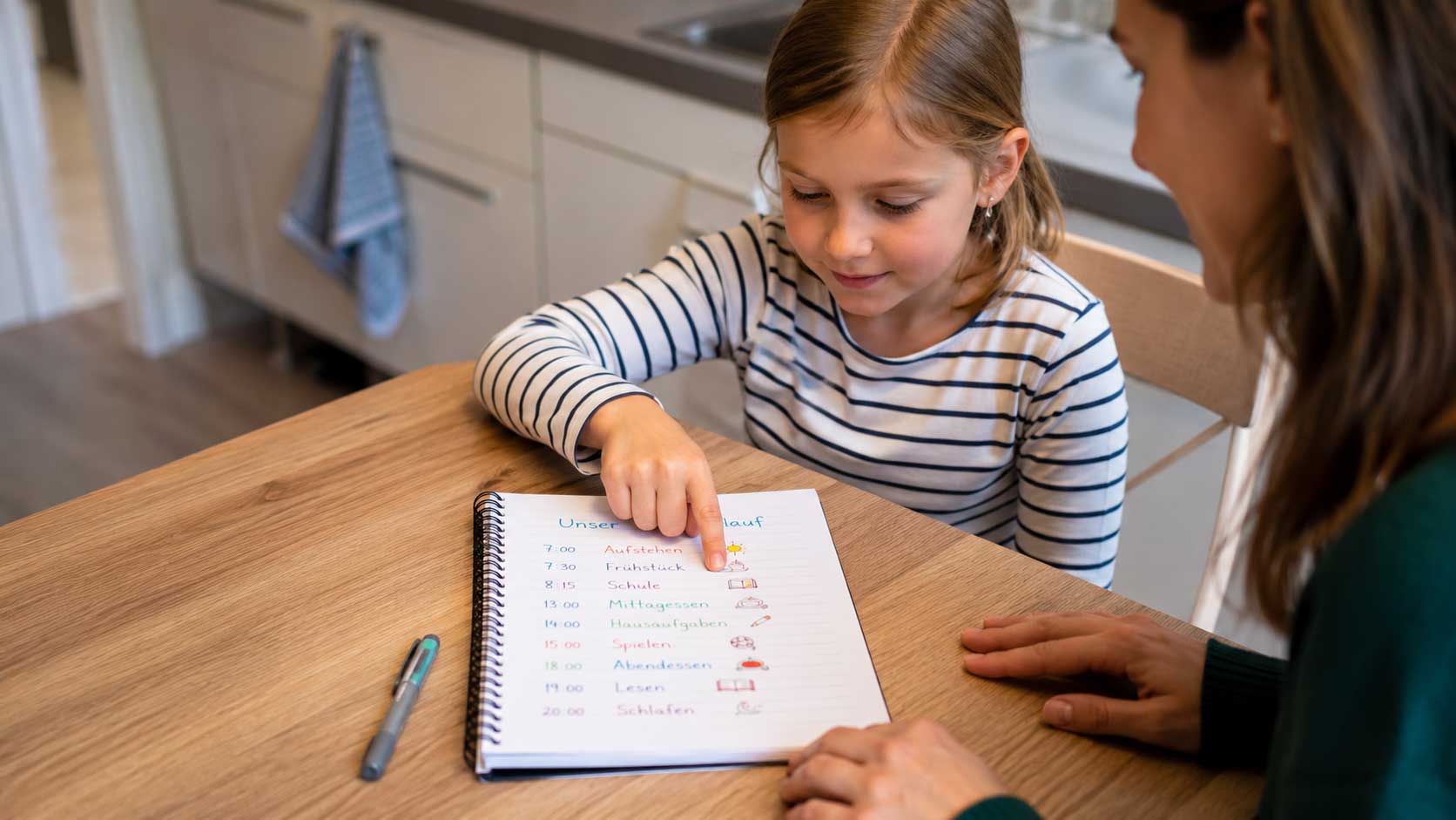 Notizblock auf dem Küchentisch mit Stichworten zum Tagesablauf, Kind deutet auf einen Eintrag